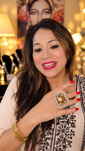 White square statement ring with pearl detailing and a gold-tone center worn on a hand